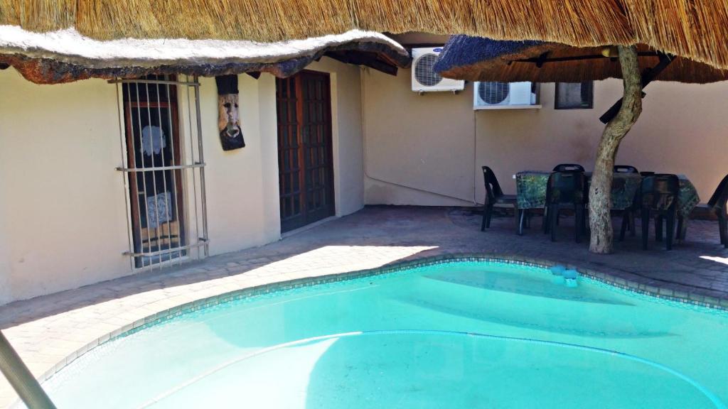 uma piscina com um guarda-sol e uma casa em Lani's Guest House - No Loadshedding em Musina