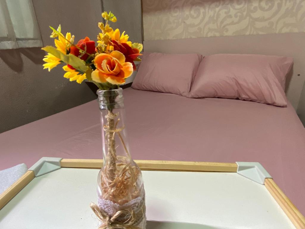 a vase with flowers on a table with a bed at Doce lar da Be in Ribeirão Preto