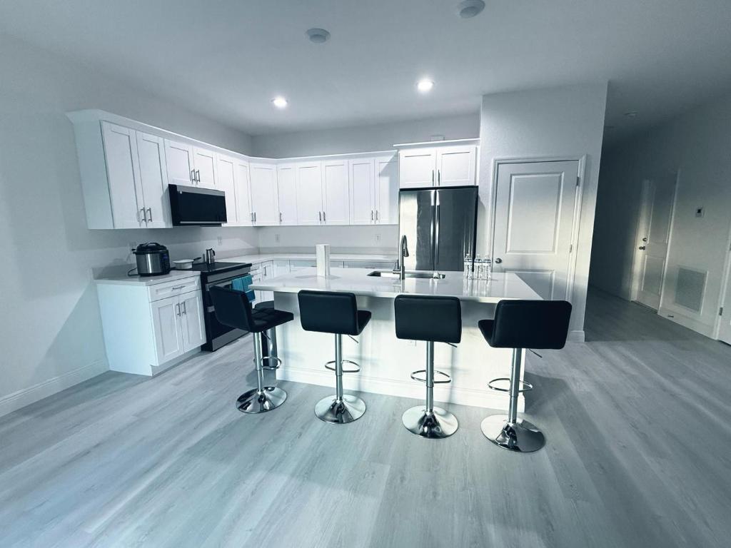 una cucina bianca con sgabelli da bar al centro di Casa compartida vacacional a La Belle