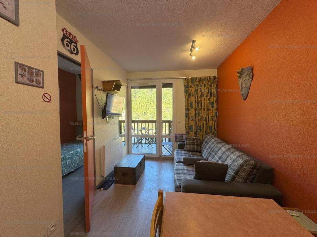 - un salon avec des murs orange et un canapé dans l'établissement Appartement F2 au pied des pistes - 5 couchages avec Wi-Fi et parking - FR-1-295-206, aux Angles