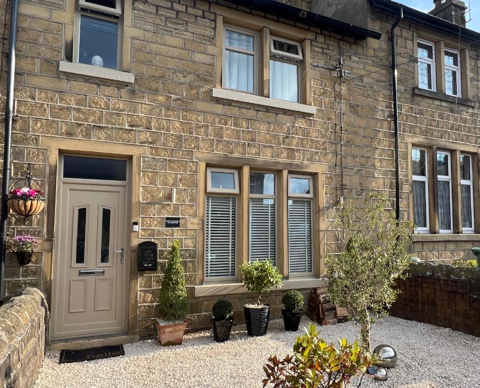a brick house with a door and potted plants at Olive Tree Cottage in Golcar