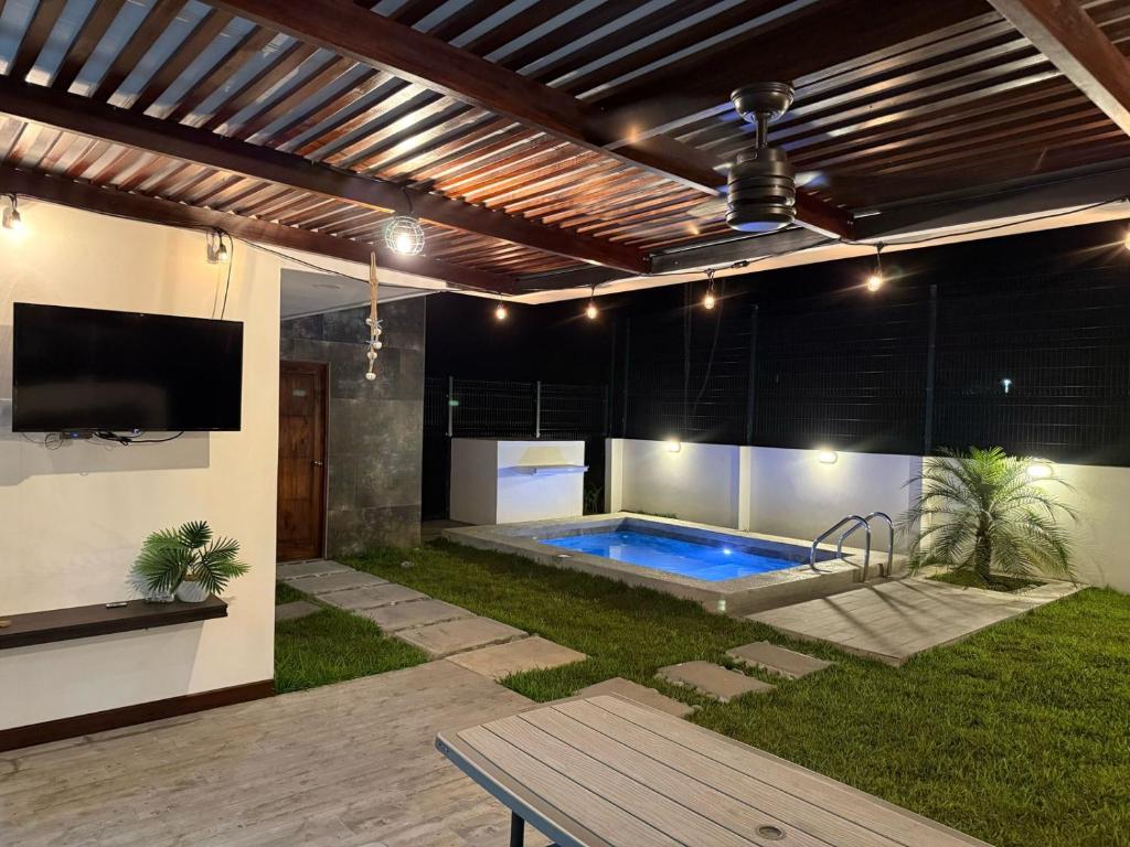 a swimming pool in a backyard with a tv and a patio at Casa kai in Agujas
