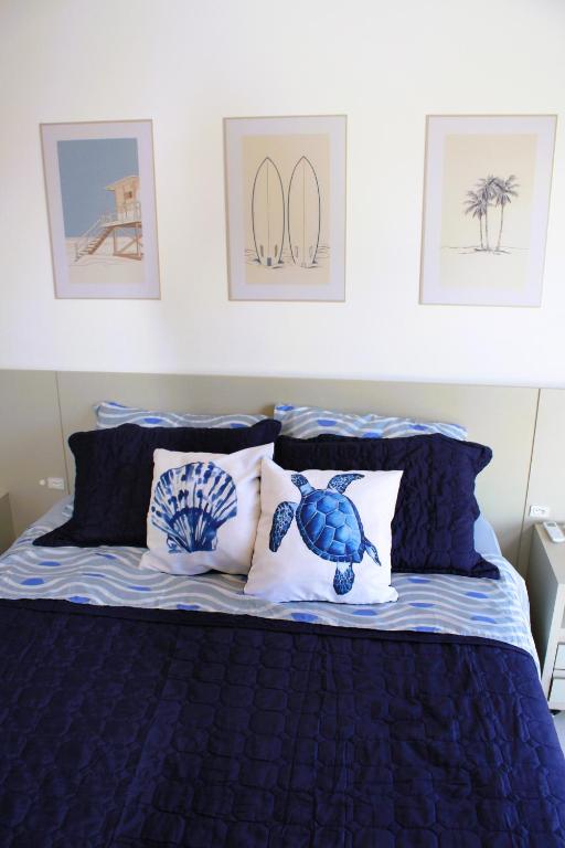 a bed with blue and white pillows and pictures on the wall at Apto de duas suítes com vista mar - 100 metros da praia em Canasvieiras in Florianópolis