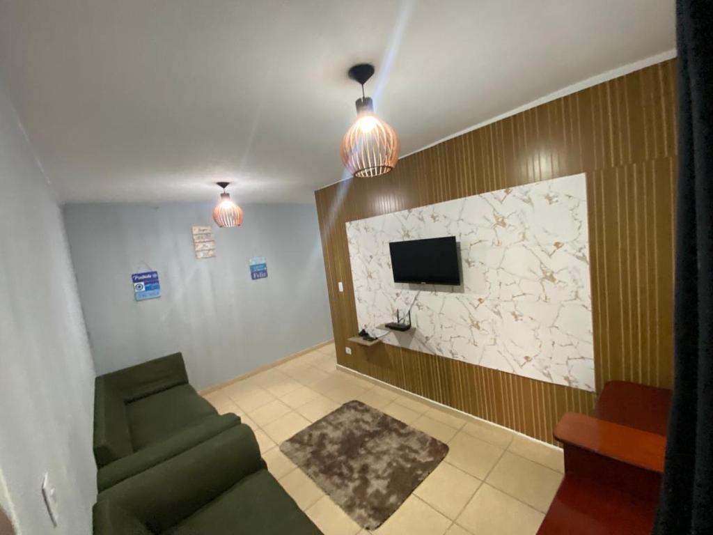 a living room with a couch and a tv at Paraíso Montanha e Mar in Peruíbe