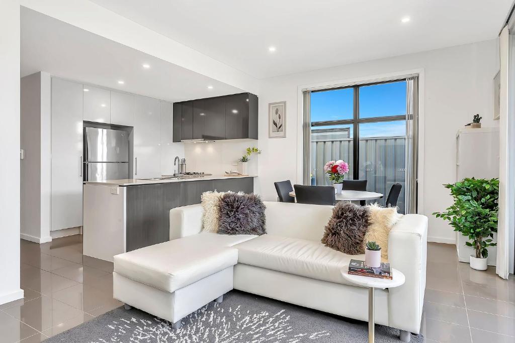 Una sala de estar con un sofá blanco y una cocina. en Luxurious Living in St Clair with Spa and Balcony, en Finsbury