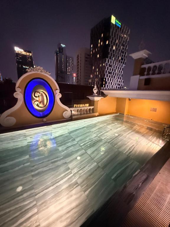 A rooftop swimming pool lit at night against Bangkok’s illuminated high-rise skyline.