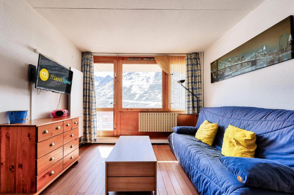 un salon avec un canapé bleu et une table dans l'établissement Résidence Le Tourmalet - maeva Home - Appartement 3 pièces 6 personnes - Confort MAE-9821, à La Mongie