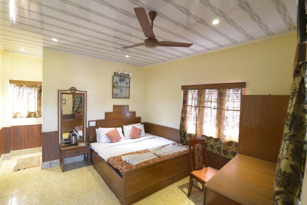 um quarto com uma cama e uma ventoinha de tecto em Tusker Towers em Thekkady