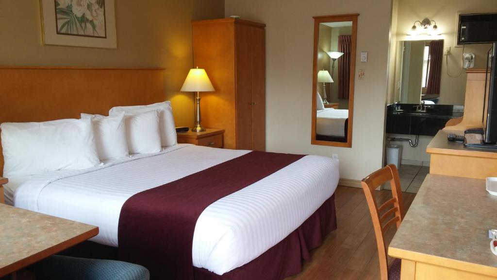ein Hotelzimmer mit einem großen Bett und einer Küche in der Unterkunft Canadas Best Value Inn & Suites-Vernon in Vernon