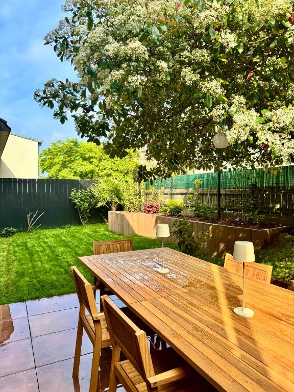 une table en bois dans une cour avec des chaises et un arbre dans l'établissement La Maison d Ernest, avec jardin, à deux pas de la gare, à Rennes