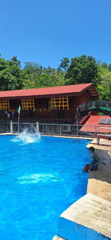 a large pool of blue water in front of a building at Twin Hearts Resort Pool Cabin 2 in Jasaan
