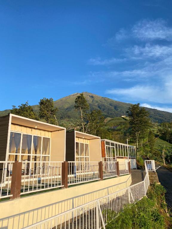 a house with a fence and mountains in the background at Cepogo Cabin Mangli Cabin Keluarga & Syariah in Prampelan