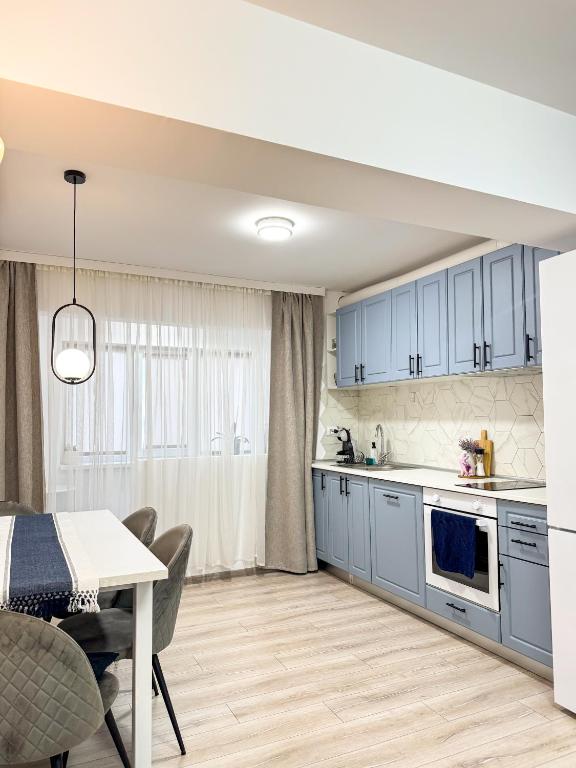 a kitchen with blue cabinets and a dining table at Iris Apartment in Craiova