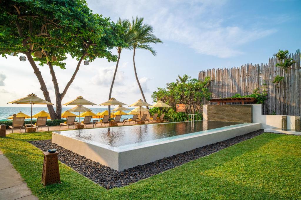 a pool at the beach with chairs and umbrellas at Buri Rasa Village Samui Adults Only in Chaweng