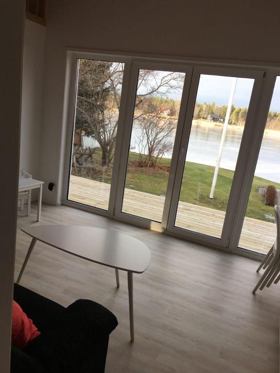 a living room with a table and large windows at Sjöstuga, lake view cottage in Spersboda