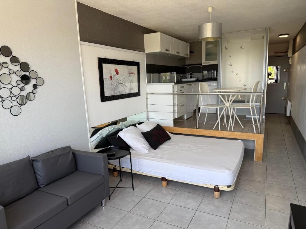 Cette chambre comprend un lit, un canapé et une cuisine. dans l'établissement Beau studio sur coursives à Port Nature au village naturiste, au Cap d'Agde