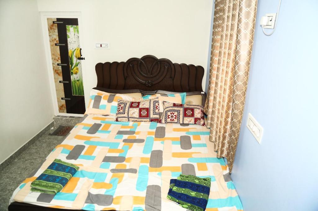 ein Bett mit einer Decke und Kissen darauf in der Unterkunft GK RESIDENCY in Tiruvidaimarudūr