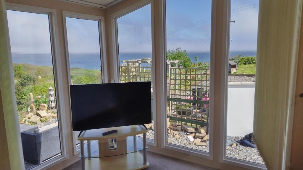 a flat screen tv sitting in front of a window at Seaside chalet in Ardmore with breathtaking views in Ardmore
