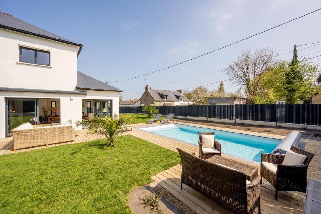 une cour arrière avec une piscine et une maison dans l'établissement Villa du Clos Briens - Piscine Privée, à Quessoy