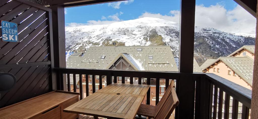 un balcone con una panca di legno e una montagna coperta di neve di Le Crey du Quart a Valmeinier