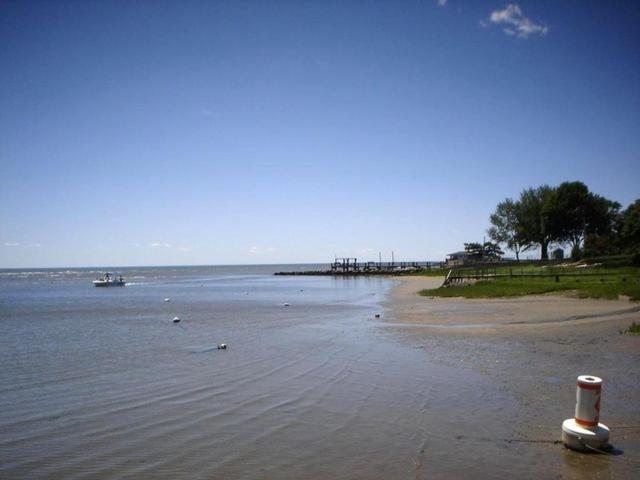 a beach with a pole in the middle of the water at Saybrook Manor Beach House in Old Saybrook