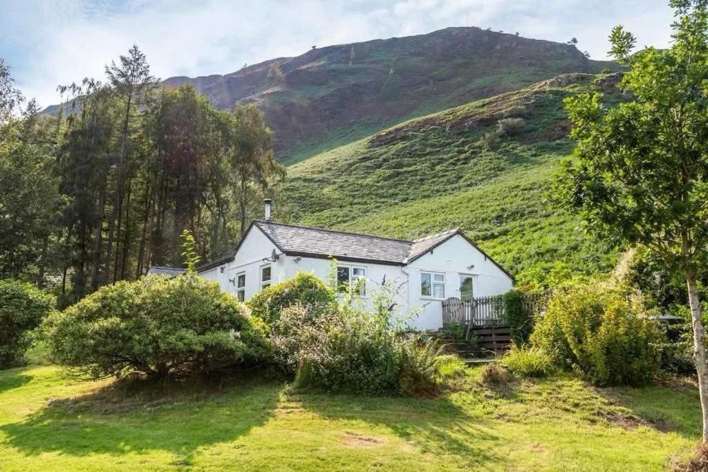 a white house with a hill in the background at Catbells Sunrise Cottage Borrowdale Lake District in Keswick