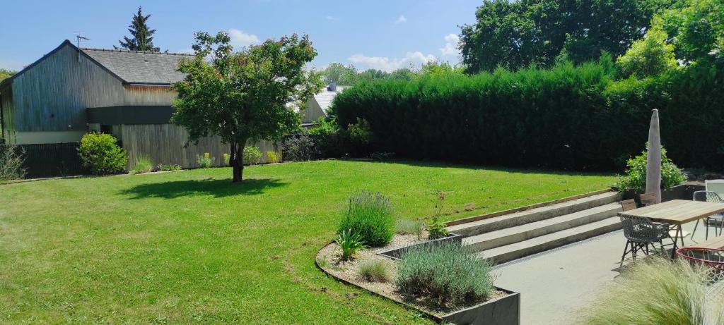 un jardin avec une table, un banc et de la pelouse dans l'établissement Maison de vacances familiale au calme entre terre et mer, à Le Minihic-sur-Rance