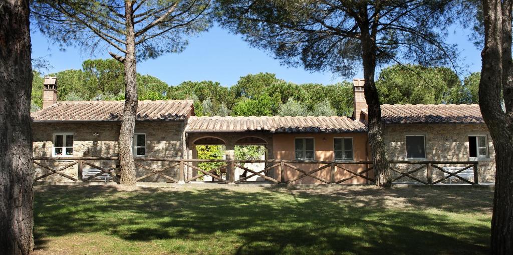 阿雷佐的住宿－Podere Poggio Mendico，一座带门和树木的古老石头房子