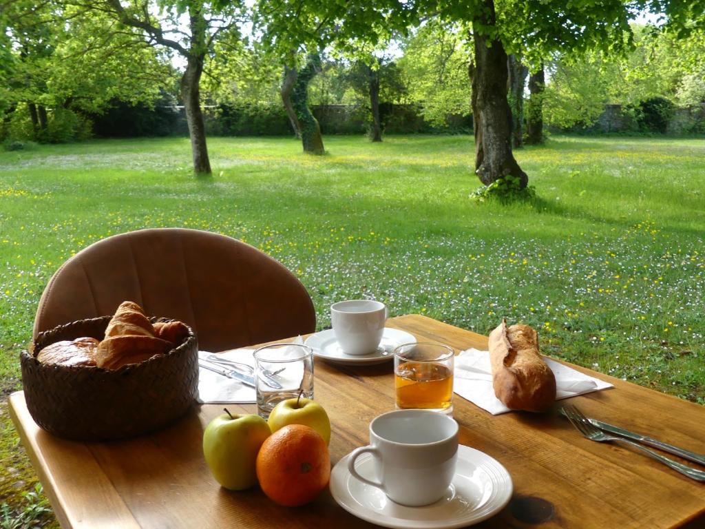 a table with bread and coffee and a basket of fruit at Hôtel et SPA du Château in Lagord