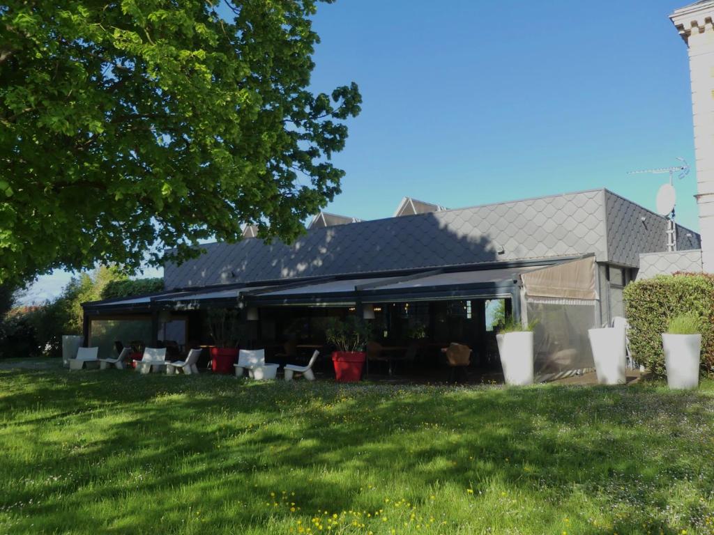 a building with a patio with chairs in a yard at Hôtel et SPA du Château in Lagord