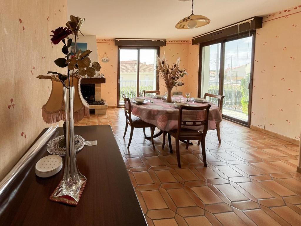 une salle à manger avec une table et un vase fleuri dans l'établissement Jolie maison avec jardin - quartier la Roulière - 4 personnes, à Givrand