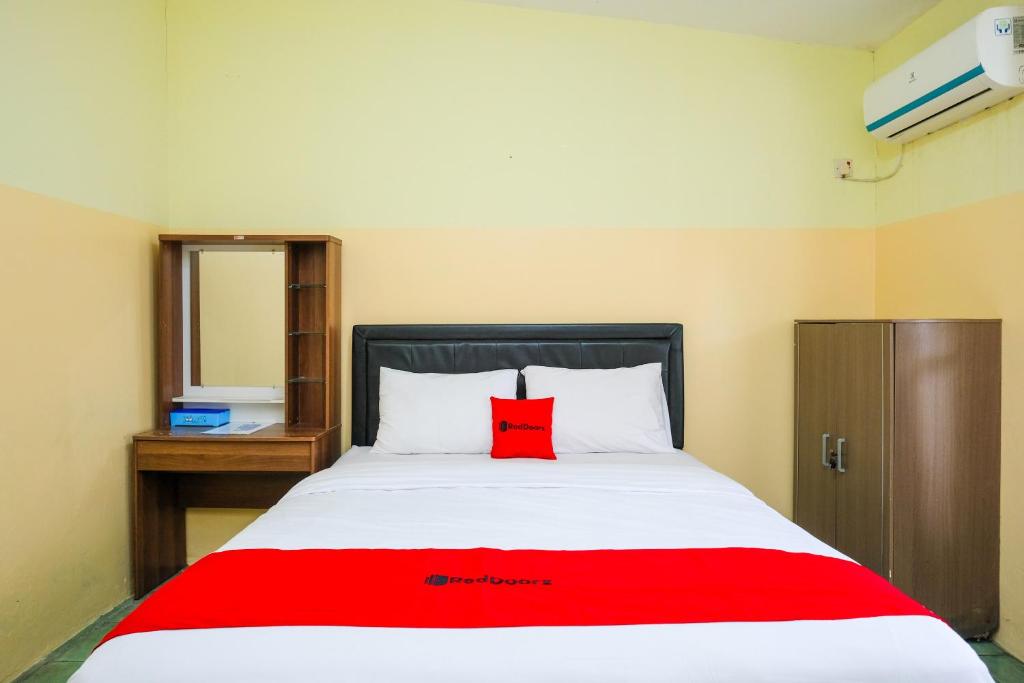 a bedroom with a red pillow on a bed at RedDoorz Syariah at Omah Pathok Malioboro in Yogyakarta