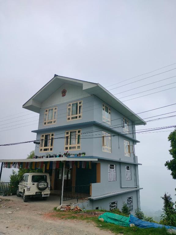 a blue house with a car parked in front of it at Valley Mist rooms & kitchen in Ravangla