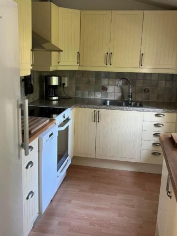 a kitchen with white cabinets and a sink at Sandskogen-Ystad in Ystad