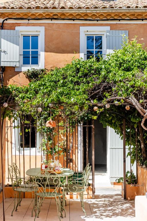 un patio avec une table et des chaises sous une pergola dans l'établissement Chez Fanny, à Bédoin