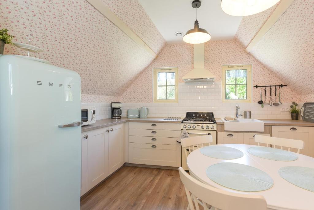 a kitchen with a table and a white refrigerator at Gite Cottage de la Douloustre in Montgaillard