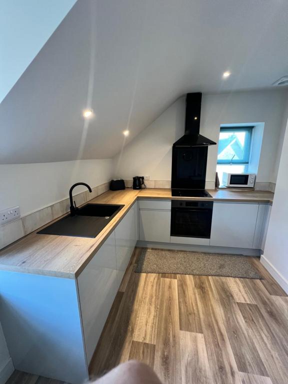 Una cocina con gabinetes blancos, un fregadero y una estufa. en torrs view apartment, en Ilfracombe
