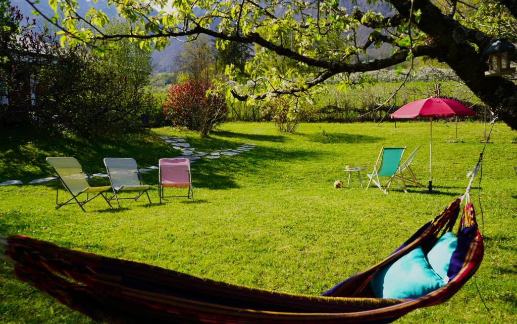 un hamac dans un champ avec des chaises et un parasol dans l'établissement Eco-gîte Belle-étoile, à Verrens-Arvey