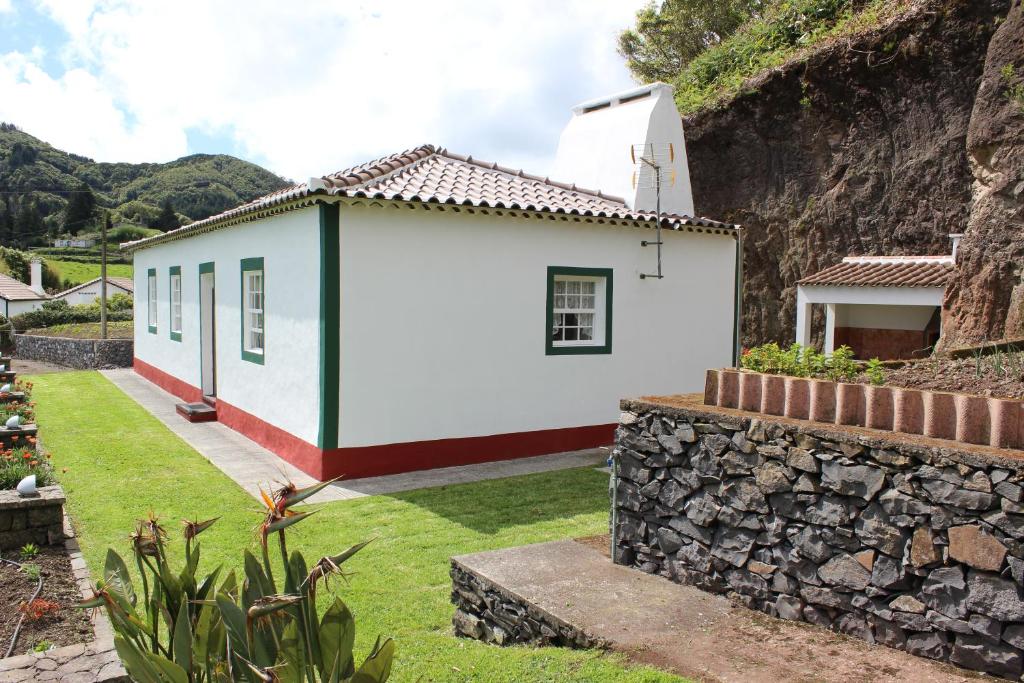 uma pequena casa branca com uma parede de pedra em Casa da Avó - Turismo Rural em Santo Espírito