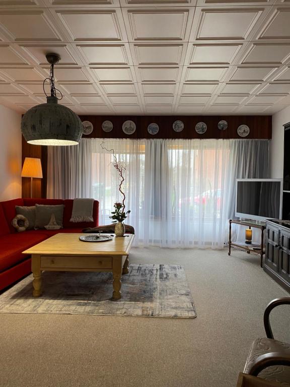 Una sala de estar con un sofá rojo y una mesa de café. en PrivArtZimmer 'Ausfahrt freihalten', en Husum