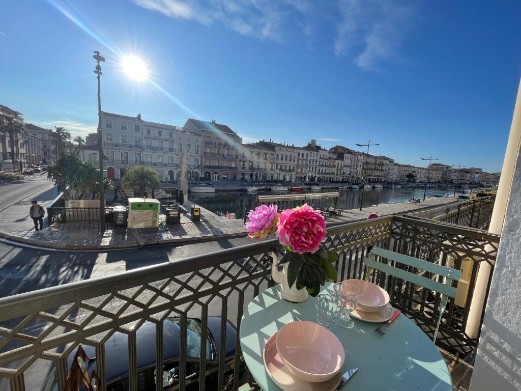 une table avec un vase de fleurs sur un balcon dans l'établissement Emplacement rare élégant appartement avec balcon sur le Canal Royal, à Sète