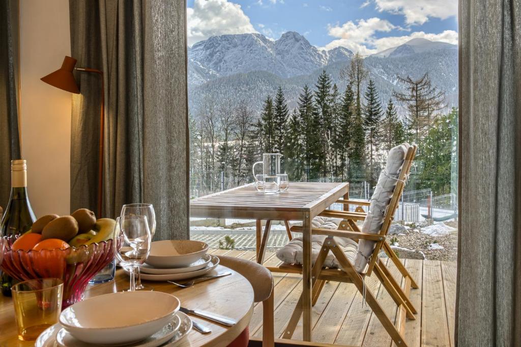 a dining room with a table and a view of mountains at TatryTop Domy Manowce z jacuzzi in Kościelisko