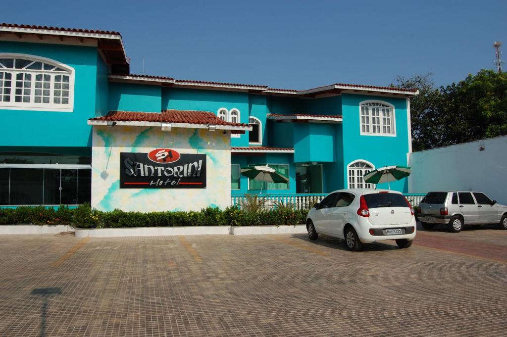 a white car parked in front of a blue building at Santorini Hotel in Santarém