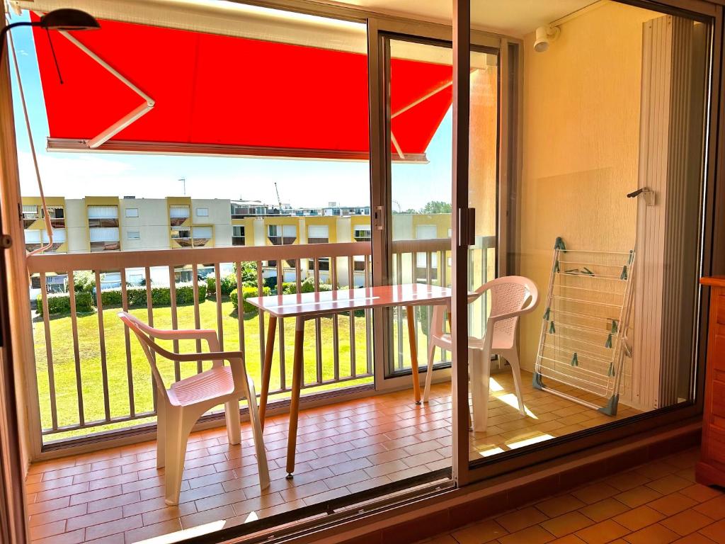 un balcon avec une table, des chaises et une fenêtre dans l'établissement Studio le grau du roi, 4 personnes, place de parking, au Grau-du-Roi