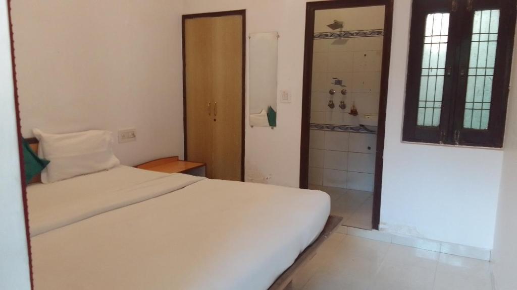 a bedroom with a white bed and a shower at ZoukStayz in Rishīkesh