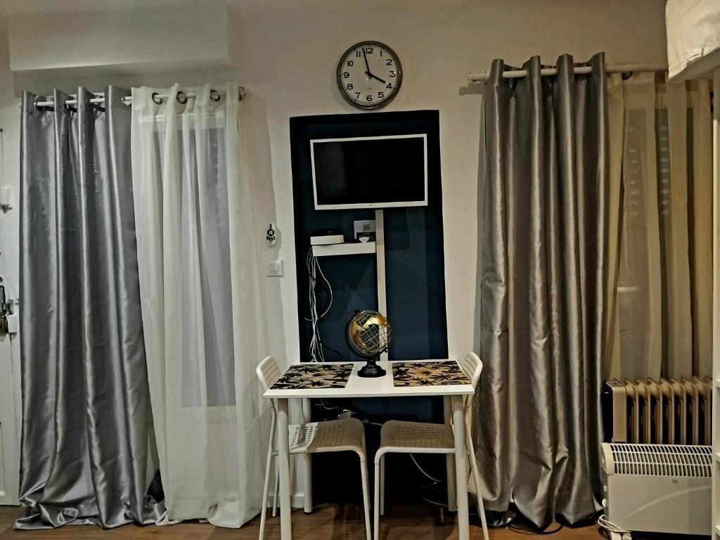 tavolo e sedie in una stanza con orologio sul muro di Petit studio proche de la defense a Puteaux