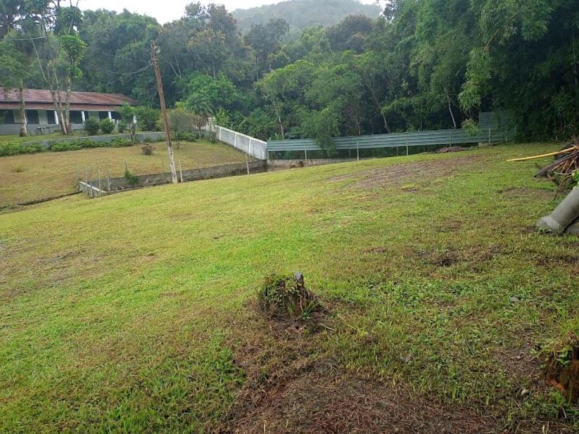 un grand champ d'herbe avec un bâtiment en arrière-plan dans l'établissement Sítio em Ribeirão Pires, à Ribeirão Pires