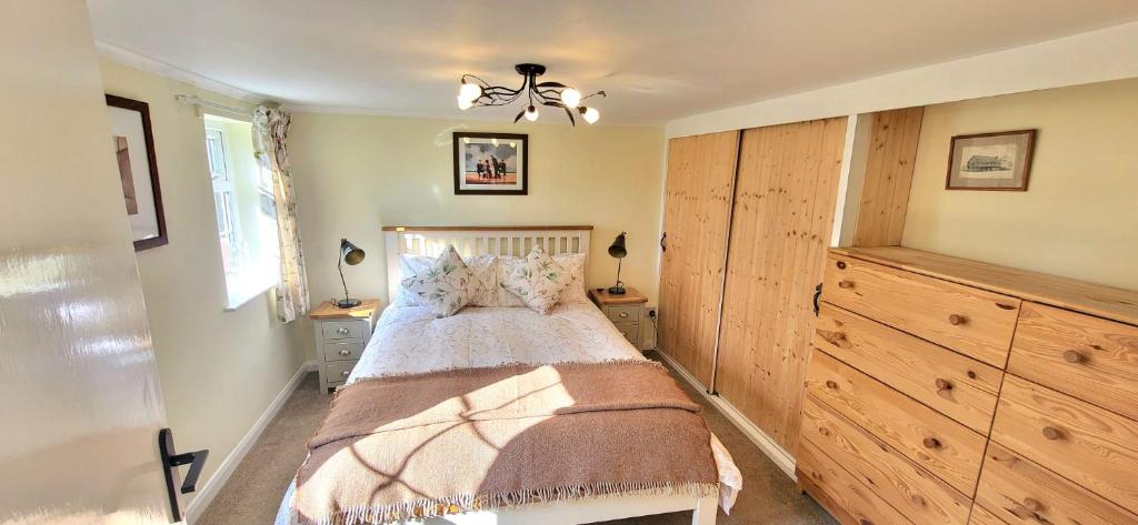 a bedroom with a bed and a dresser at Conifer Cottage in North Somercotes