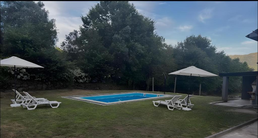 a swimming pool with two chairs and an umbrella at Casa Santo Antonio in Antas