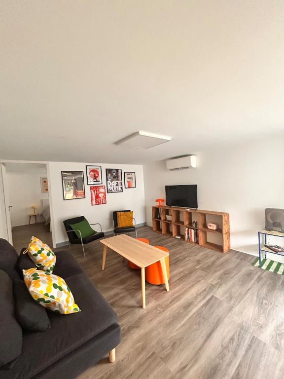 un salon avec un canapé et une table dans l'établissement Appartement rétro nature avec jardin 15 min Toulouse centre, à Saint-Geniès-Bellevue